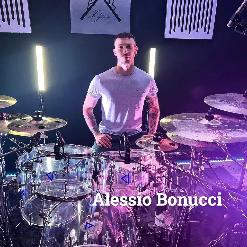Il batterista Alessio Bonucci siede dietro una batteria trasparente in uno studio illuminato da luci LED viola e bianche