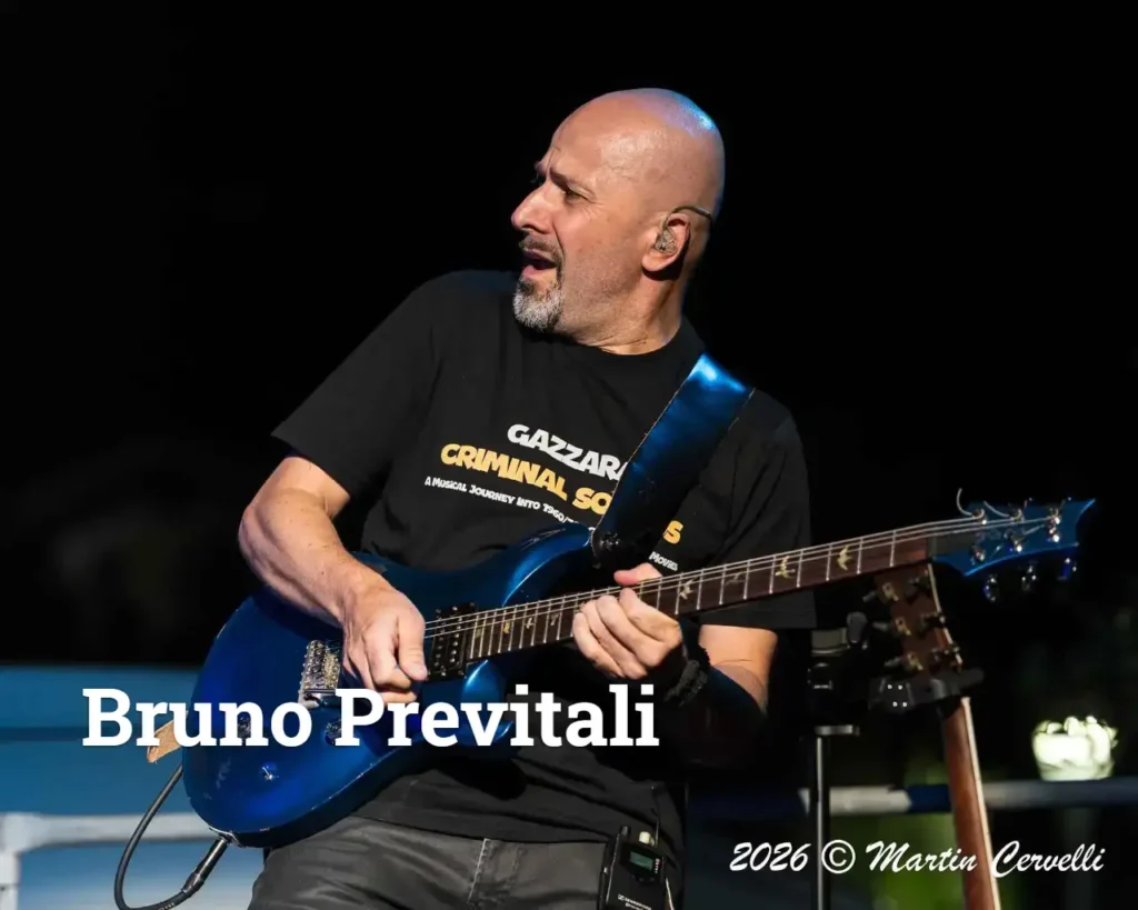 Bruno Previtali suona la chitarra elettrica blu sul palco durante il tour 2026, indossando una maglietta nera con scritte