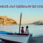 Due bambini guardano il mare di Ischia seduti su una barca chiamata Achillea, con il Castello Aragonese sullo sfondo