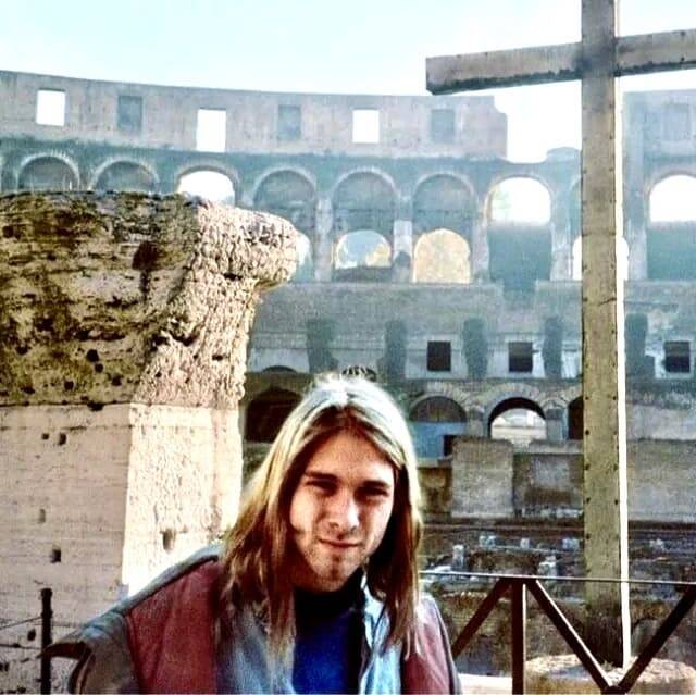 Kurt Cobain dei Nirvana in posa davanti al Colosseo durante il suo tour in Italia, con una croce in primo piano