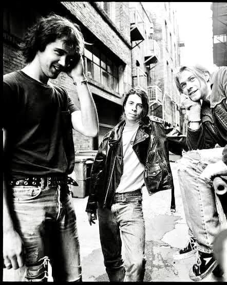 I Nirvana in posa in un vicolo durante il loro tour in Italia, con Kurt Cobain, Dave Grohl e Krist Novoselic in abiti casual