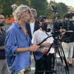 Troupe cinematografica al lavoro sul set del film Gelato al cioccolato a Milano con cinepresa su cavalletto e ciak in primo