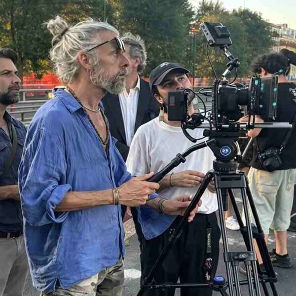 Troupe cinematografica al lavoro sul set del film Gelato al cioccolato a Milano con cinepresa su cavalletto e ciak in primo