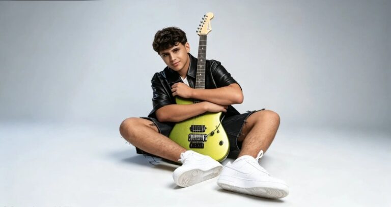 Matteo Trullu, protagonista di JESC 2026, seduto a terra con una chitarra elettrica verde e abbigliamento casual su sfondo