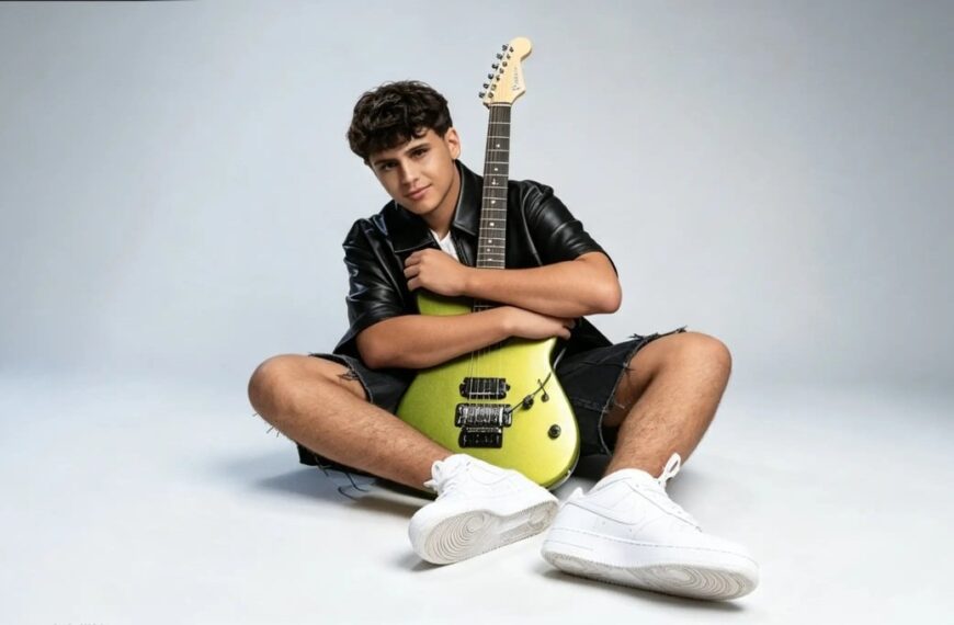 Matteo Trullu, protagonista di JESC 2026, seduto a terra con una chitarra elettrica verde e abbigliamento casual su sfondo
