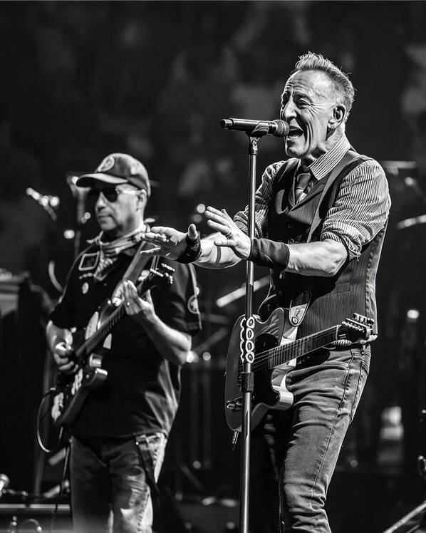 Bruce Springsteen canta al microfono con la chitarra a tracolla accanto a un musicista durante il Philadelphia Freedom Cut