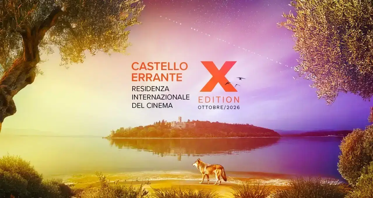 Un lupo cammina sulla riva del Lago Trasimeno davanti all'Isola Polvese sotto un cielo sfumato per il Castello Errante 2026