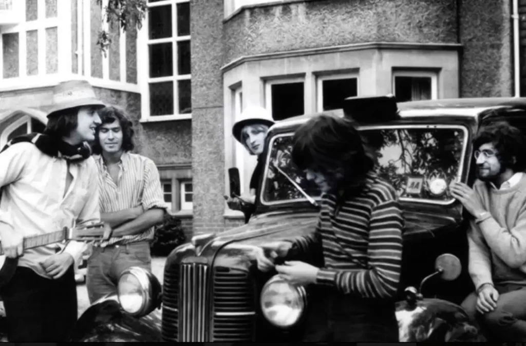I membri dei Genesis posano accanto a un'auto d'epoca durante le sessioni di registrazione di From Genesis to Revelation
