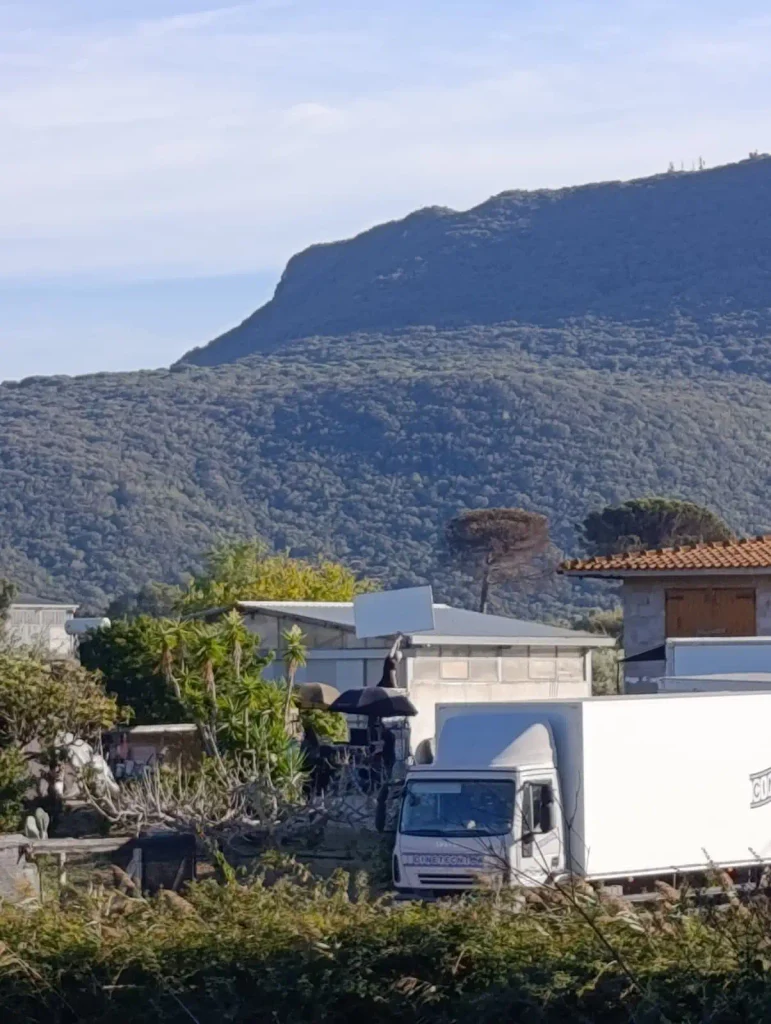 Set cinematografico del film Go con un camion della produzione Kinetecnica parcheggiato davanti a un edificio in provincia