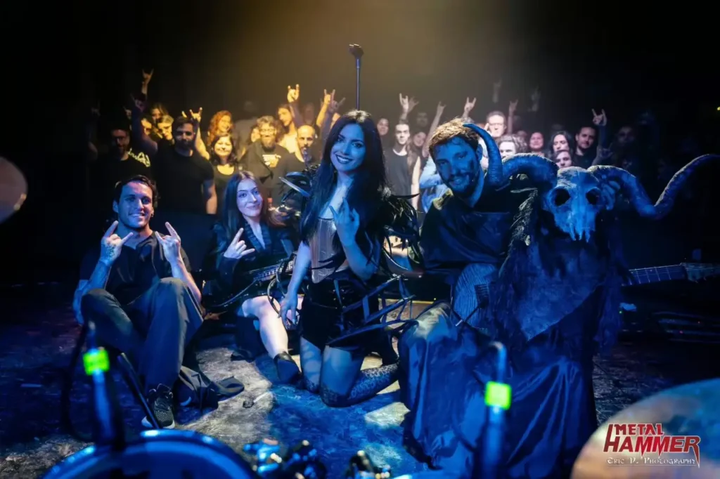 Irene Petitto posa sul palco con la sua band metal e un musicista mascherato con un teschio di capra davanti al pubblico