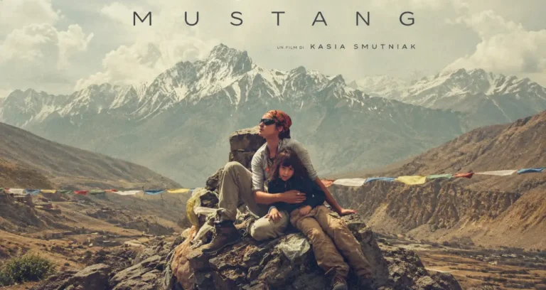 Kasia Smutniak abbraccia una bambina seduta su una roccia davanti alle montagne innevate nel documentario Mustang