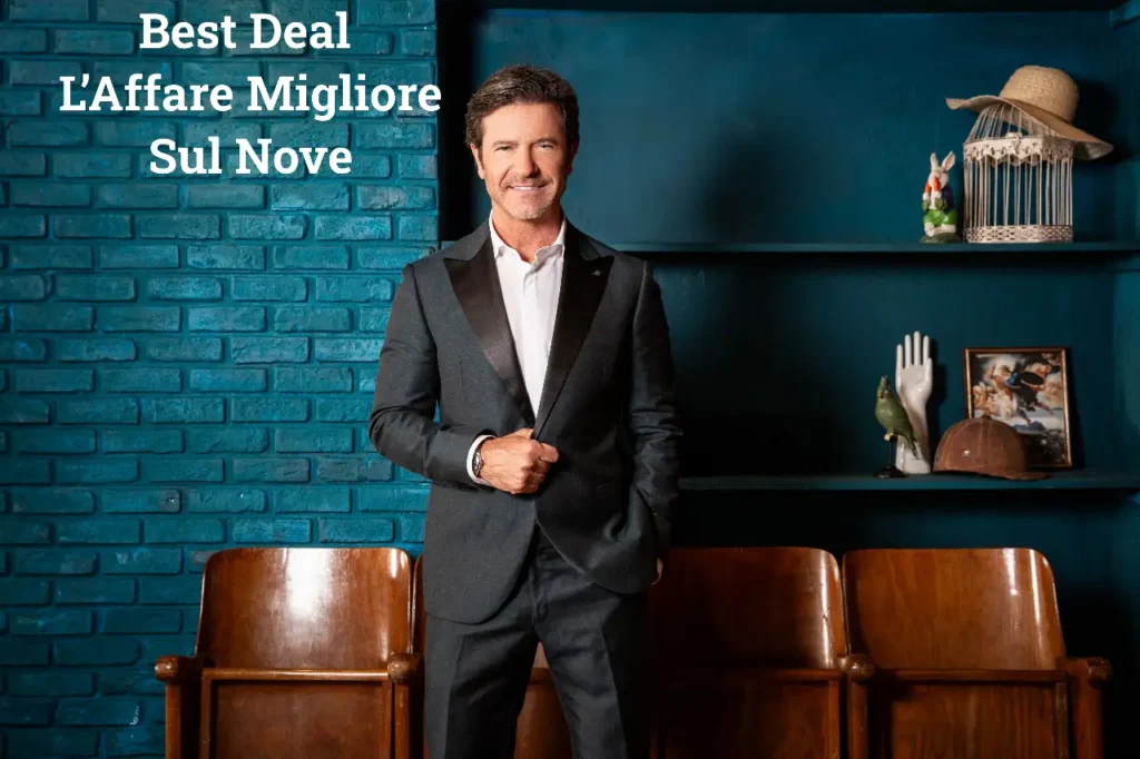 Paolo Conticini in giacca scura posa davanti a una parete blu con la scritta Best Deal – L’Affare Migliore e oggetti