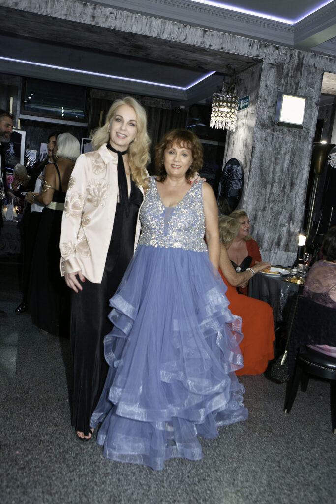 Maria Pia Cappello festeggia il suo compleanno indossando un abito azzurro in tulle accanto a un'ospite in giacca rosa