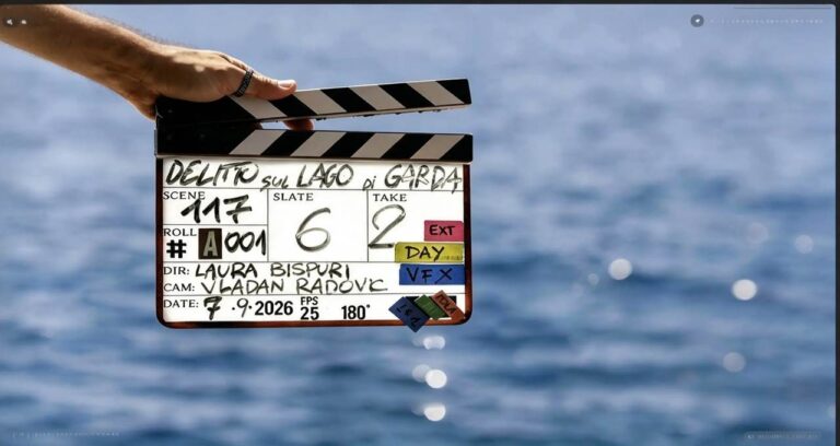 Ciak della serie originale Disney+ Delitto sul Lago di Garda tenuto da una mano davanti alle acque blu del lago