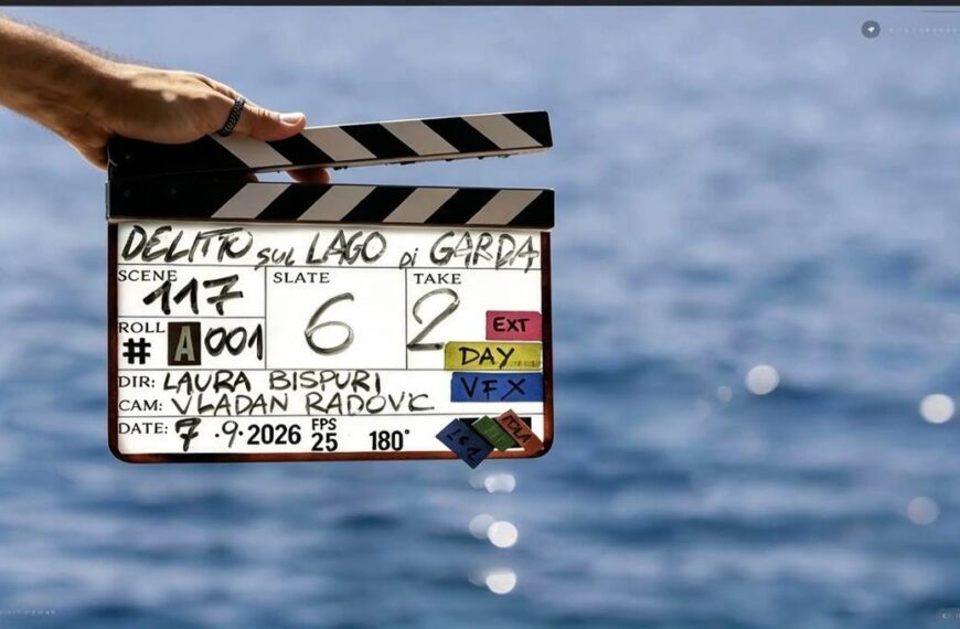 Ciak della serie originale Disney+ Delitto sul Lago di Garda tenuto da una mano davanti alle acque blu del lago