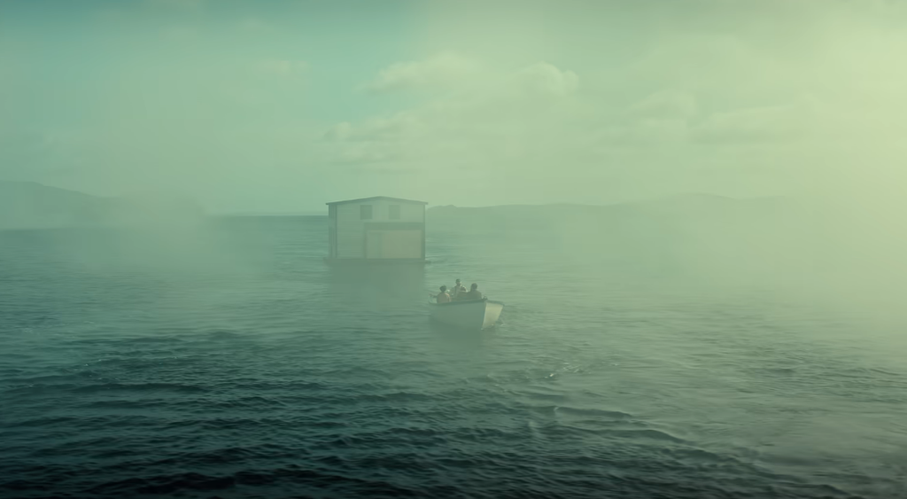 Barca con tre persone che si avvicina a una casa galleggiante in mare avvolto da foschia verde tenue