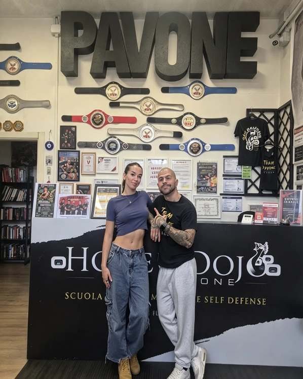 Matilde Crescentini posa accanto al maestro Marco Pavone nella palestra Honbu Dojo Pavone, decorata con cinture da campione