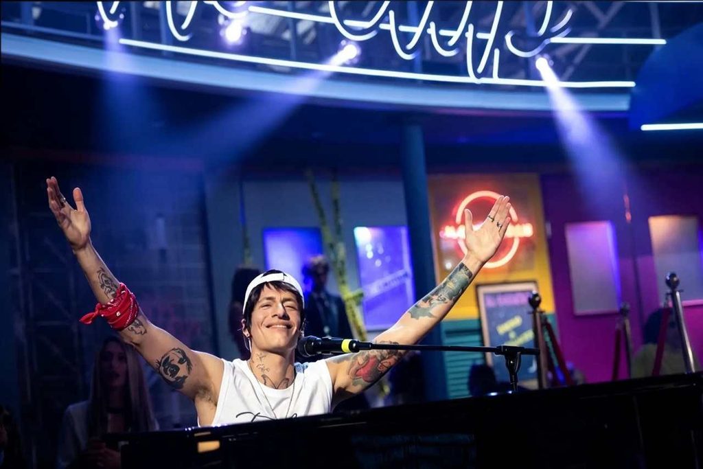 Giovanni Vernia nei panni di Terzultimo, con le braccia alzate al pianoforte durante la sua parodia al GialappaShow