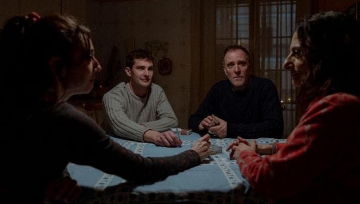 Quattro persone siedono attorno a un tavolo coperto da una tovaglia azzurra in una scena del film La città dei vivi