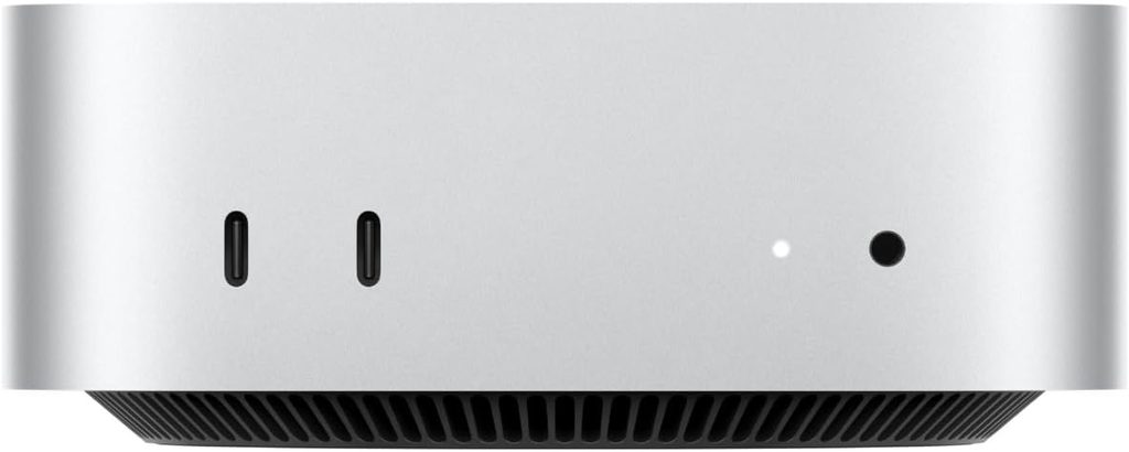Mac mini M6 argento visto frontalmente con due porte USB-C a sinistra, spia LED accesa e foro jack a destra, griglia di