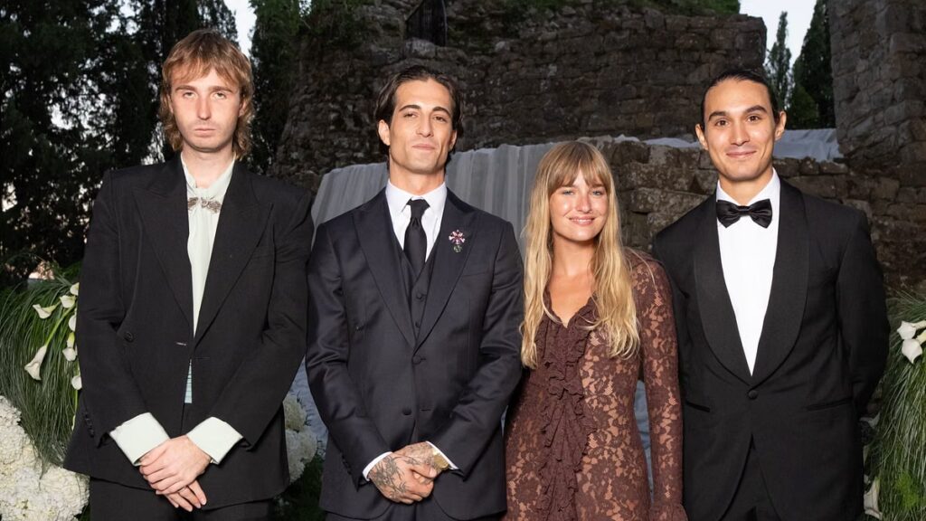 Damiano David dei Måneskin posa in completo sartoriale insieme a tre persone in un contesto elegante per una possibile